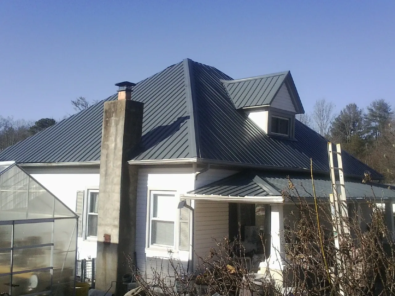 Dark blue standing seam metal roof on a white farmhouse with dormer — Slate & Tile Roof Repair by Roofing Brothers in Verbank
