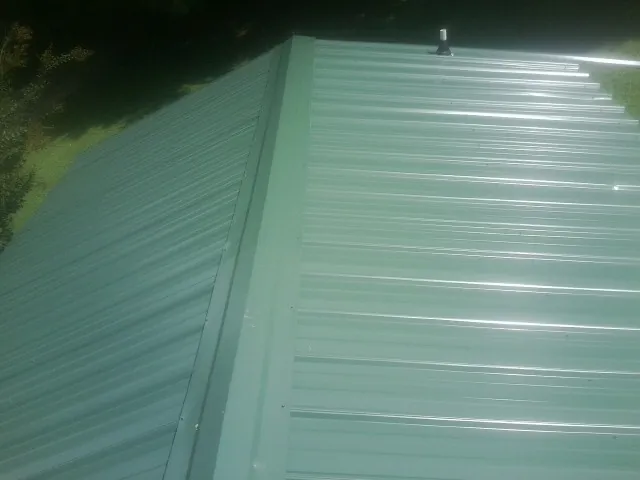 New green metal panels meeting at the ridge of a roof — Flat Roof Repair work by our crew in Verbank