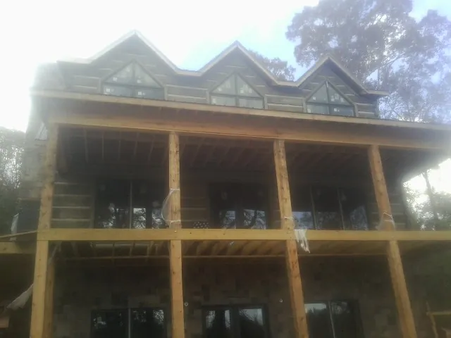 Dormers and porch framing on a large log home under construction — Roof Coating work by our crew in Verbank