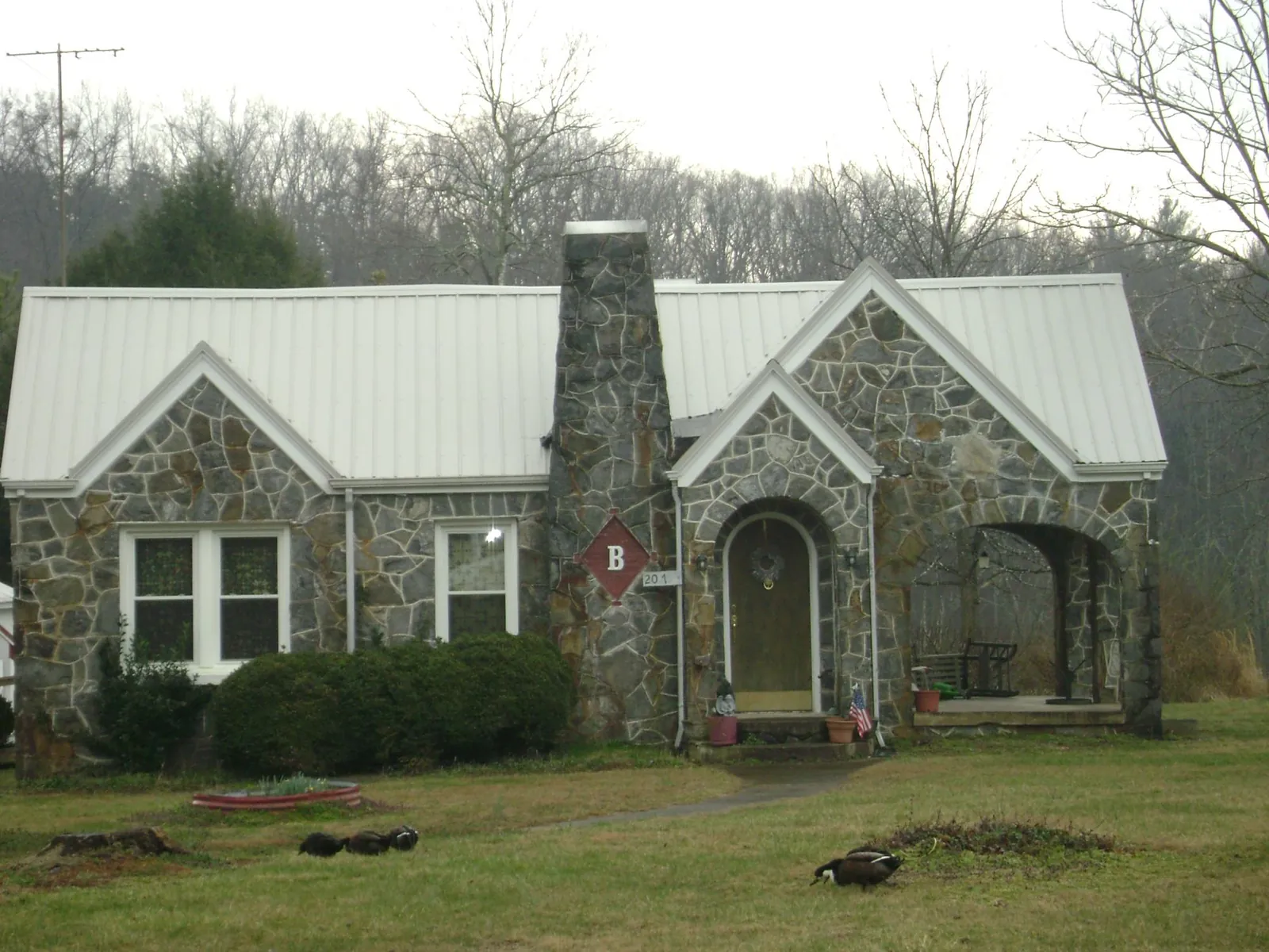 White metal roof on a stone cottage with steep gables in Verbank