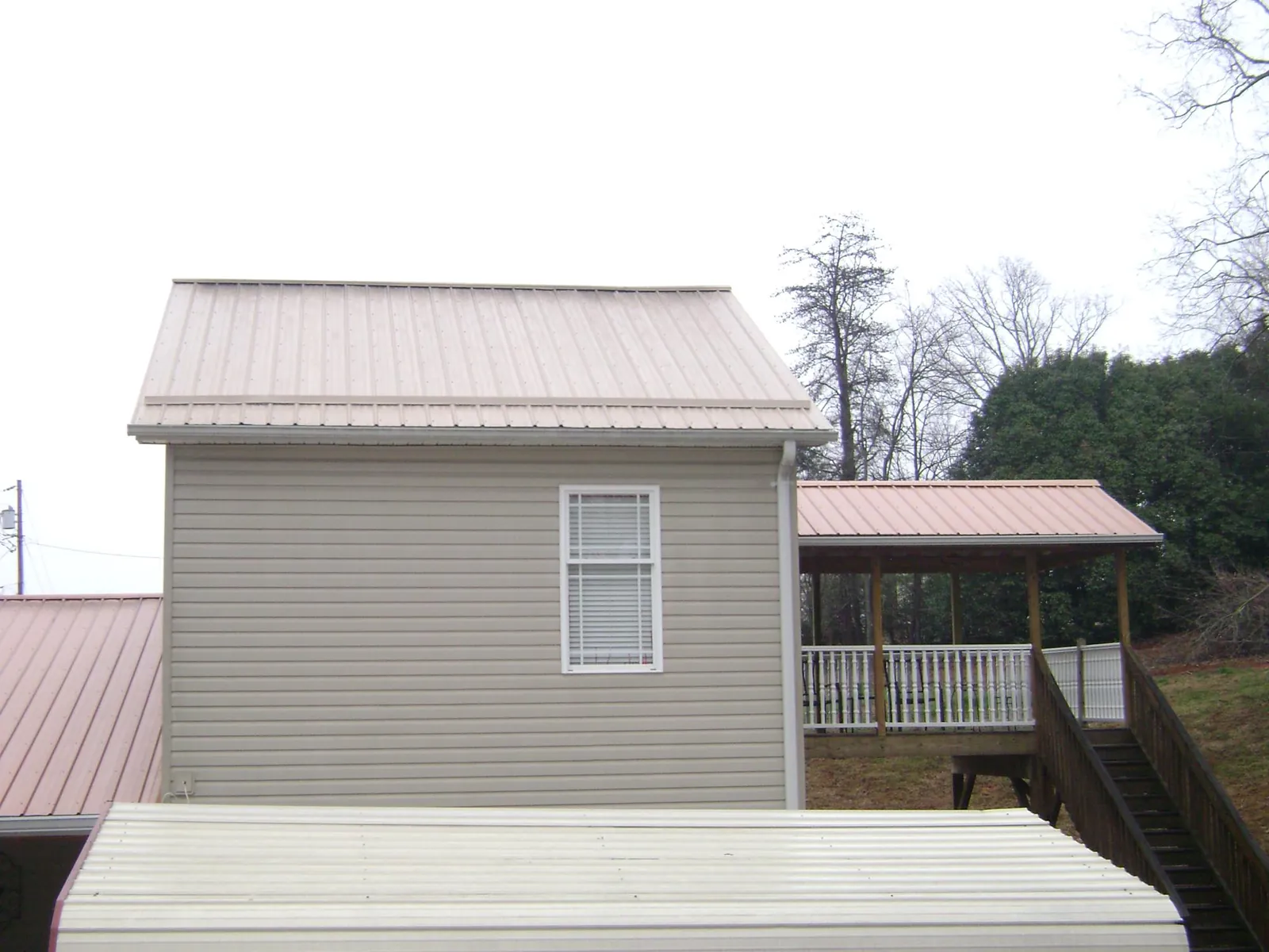 Tan metal roofs on a two story addition and attached porch, from a Roof Replacement job in Verbank