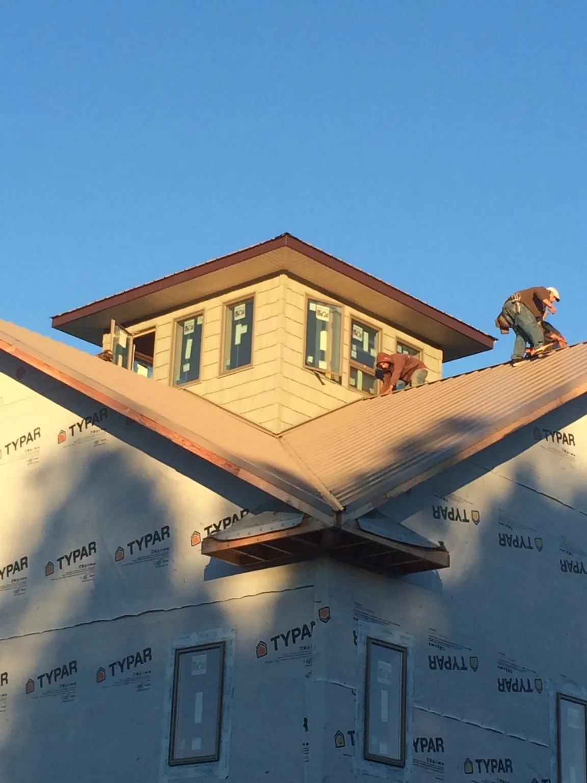 Roofers working around a rooftop cupola on a new metal roof at sunset — Roof Waterproofing in Verbank by Roofing Brothers